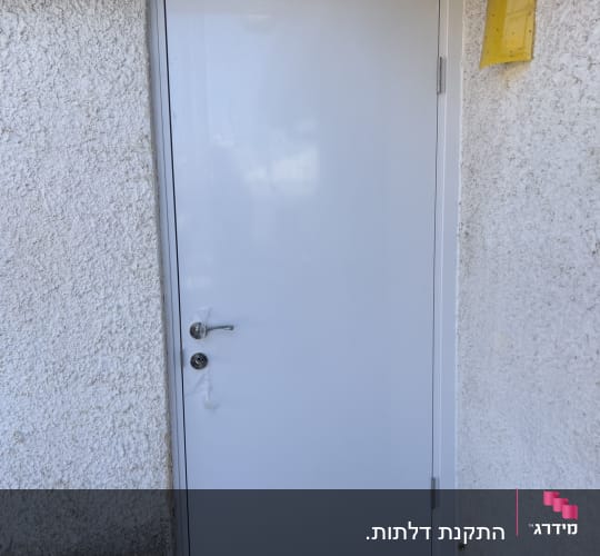 דלת לבנה מותקנת בקיר חיצוני